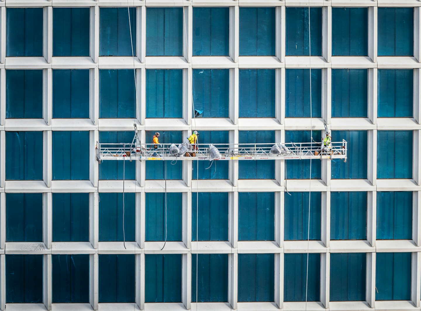 Bouwvakkers op steigers die aan een modern gebouw werken.