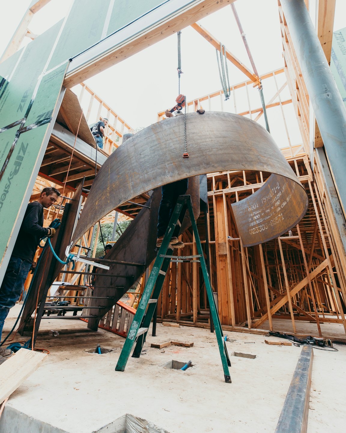 Werknemers installeren een gebogen metalen constructie in een gebouw.