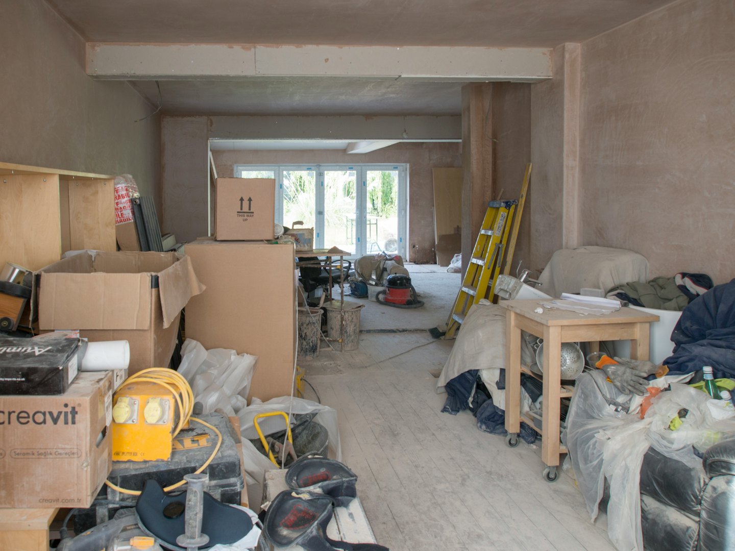 Woonkamer in renovatie met bouwmaterialen en gereedschap.
